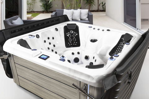 Iconic Series spa on a backyard patio with the DURA-SHIELD HardCover folded open behind it, seats and jets in full view